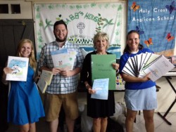 Drake team, Abby Anderson, Sean Kolodziej and Sally Beisser delivers books to Lydia Brown, Volunteer Coordinator. for Holy Cross School.