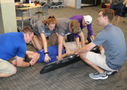 Students attempting a spine board transfer in AT lab