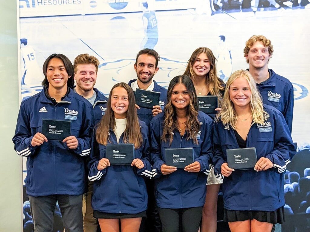First-year students in Drake University Master of Athletic Training (MAT) are pictured in a group wearing their sporty, blue wind breakers at the 2023 Blue Coat Ceremony, a rite of passage where the students are officially welcomed into the program.
