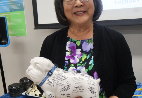 Yolanda Griffiths at retirement party holding bulldog statue signed by colleagues