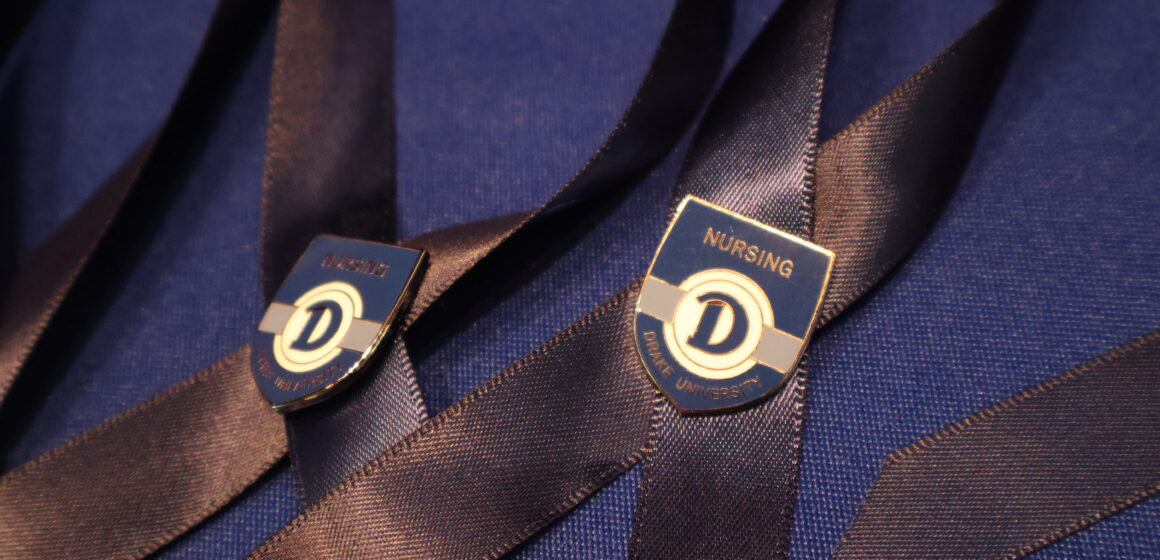Blue ribbons with shield-shaped pin attached with the Drake logo and the word Nursing