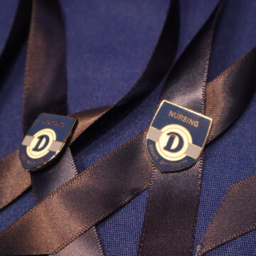 Blue ribbons with shield-shaped pin attached with the Drake logo and the word Nursing