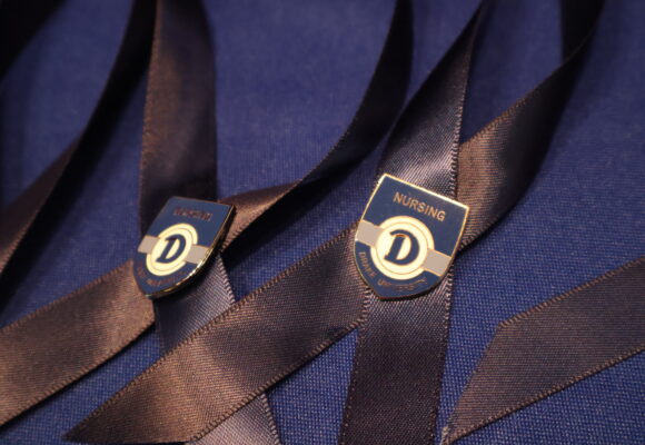 Blue ribbons with shield-shaped pin attached with the Drake logo and the word Nursing