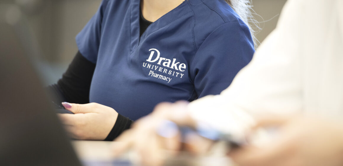 Drake pharmacy student on computer in scrubs