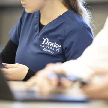 Drake pharmacy student on computer in scrubs