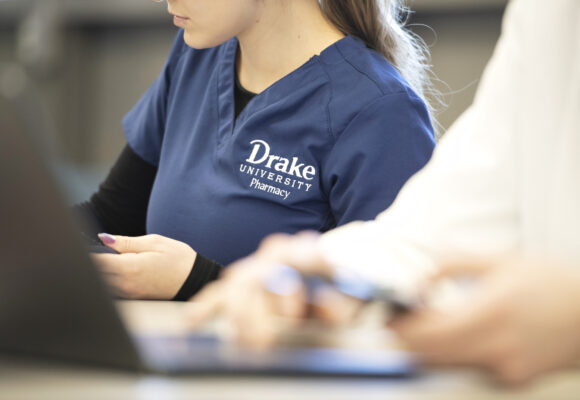 Drake pharmacy student on computer in scrubs