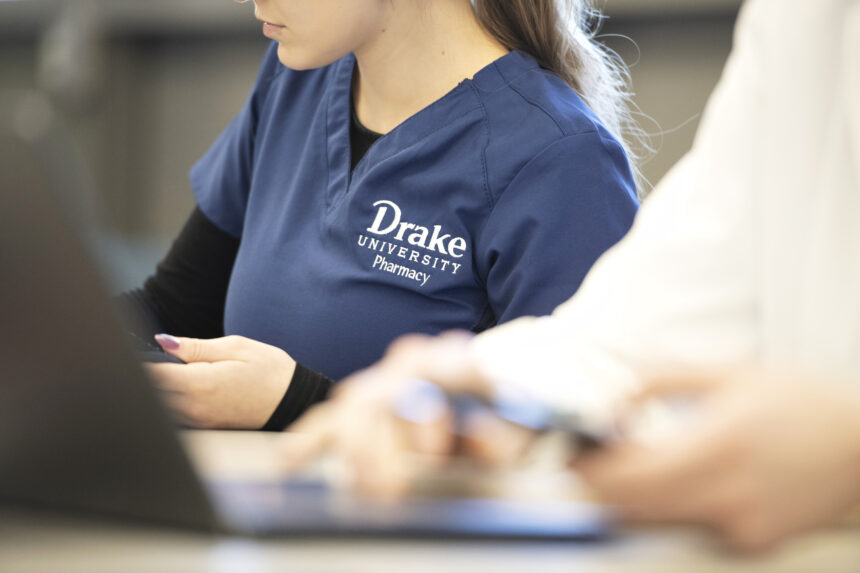 Drake pharmacy student on computer in scrubs