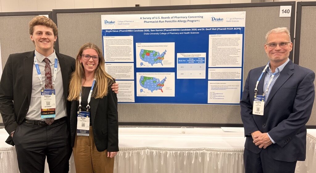 two drake pharmacy students and their faculty mentor stand next to their research poster at the conference