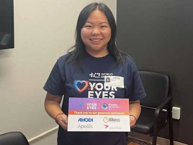 Rose Lee smiles and holds up a poster in her Prevent Blindness Iowa uniform