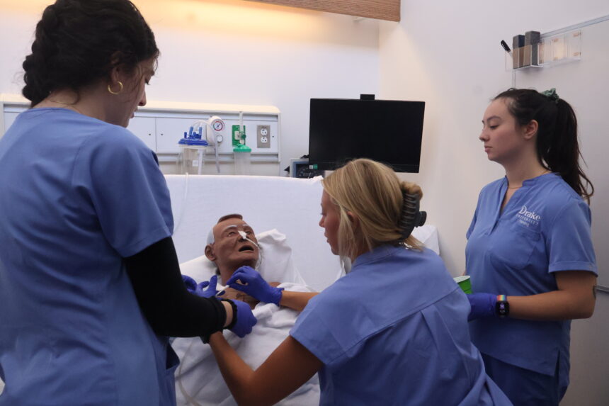 Nursing students gather around a mannekin to adjust tubing attached to his face
