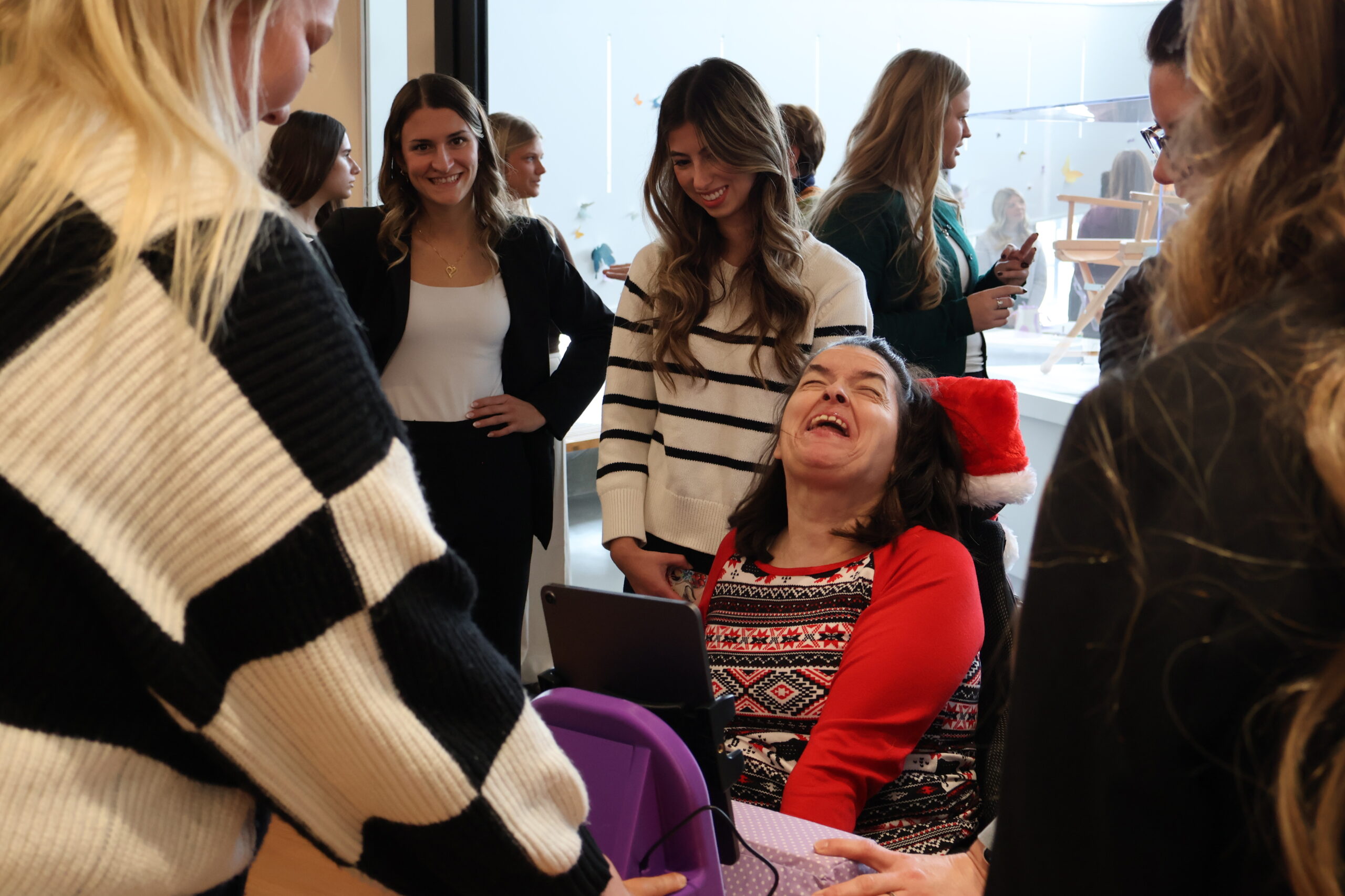 A client smiles and laughs with her purple iPad stand stand in front of her, surrounded by students watching and smiling