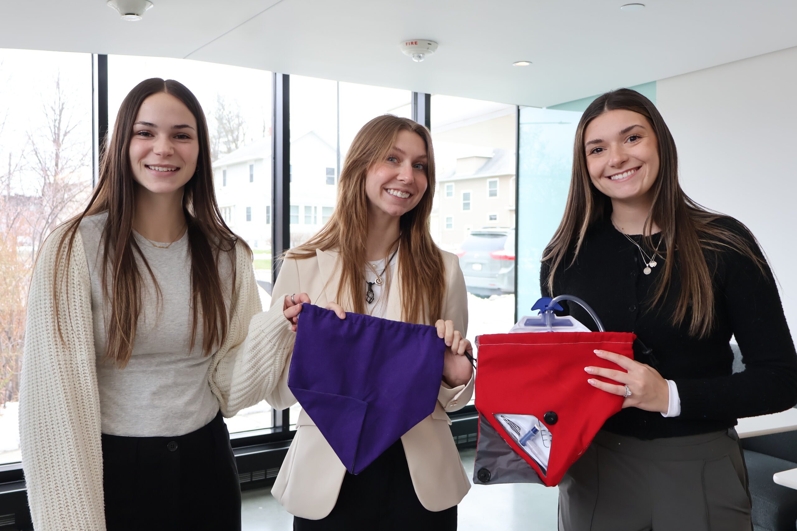 OT students smile and hold up catheter cover bags