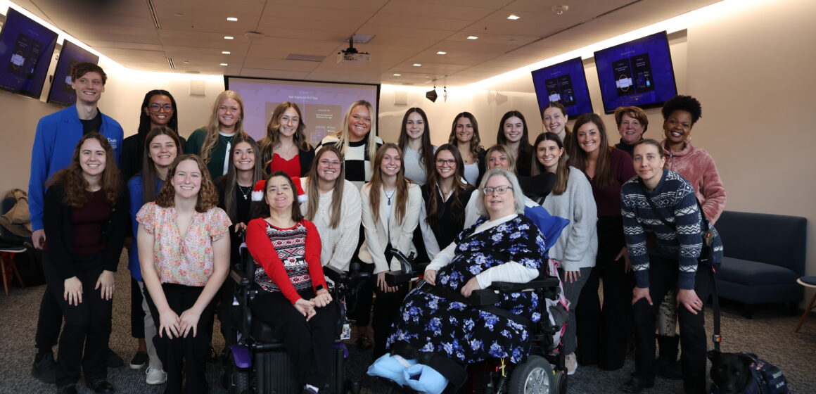 IMG_9455 A large group of students, professors and clients smile and pose together at the OT Expo