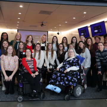 A large group of students, professors and clients smile and pose together at the OT Expo