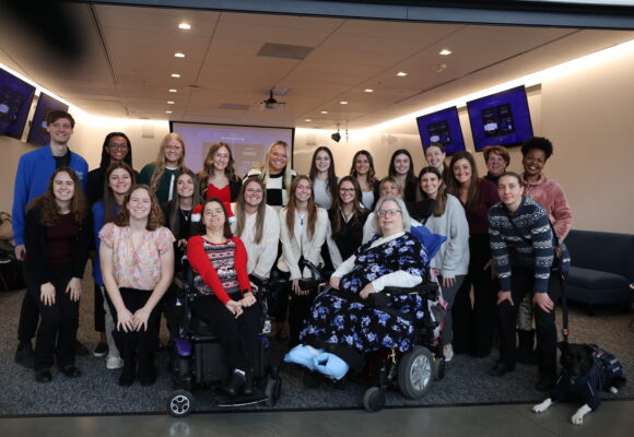 A large group of students, professors and clients smile and pose together at the OT Expo